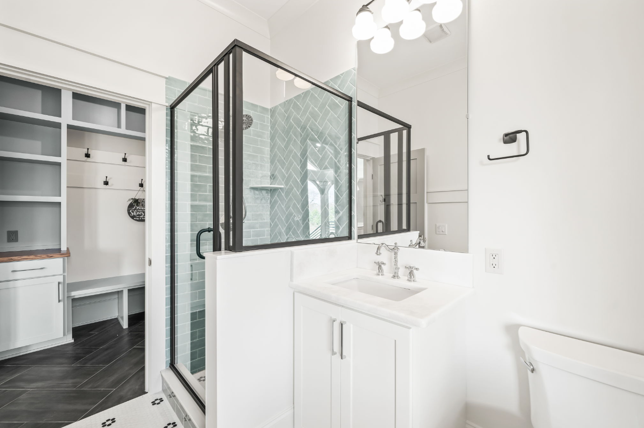 A bathroom with a walk in shower , sink , toilet and mirror.