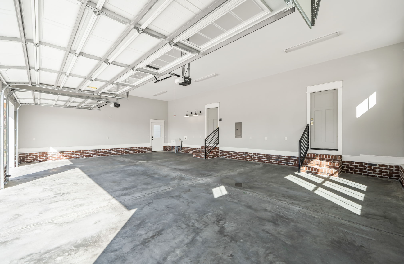 An empty garage with a garage door open and a staircase.