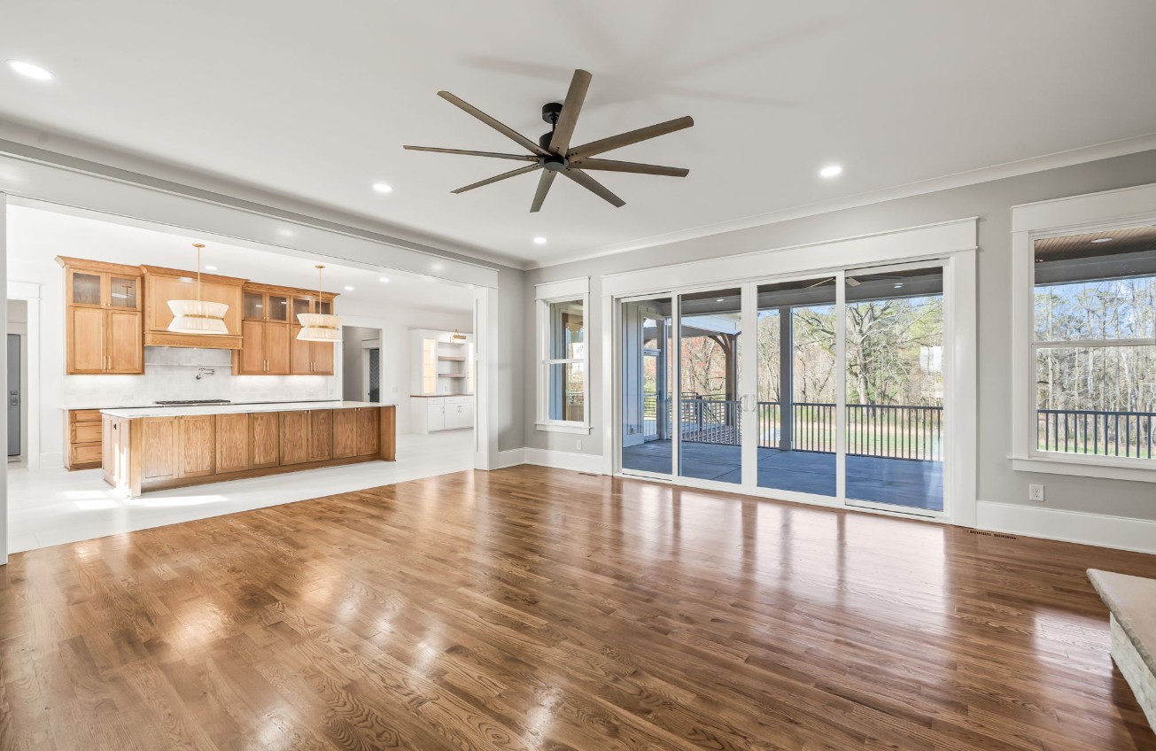 An empty living room with hardwood floors and a ceiling fan.