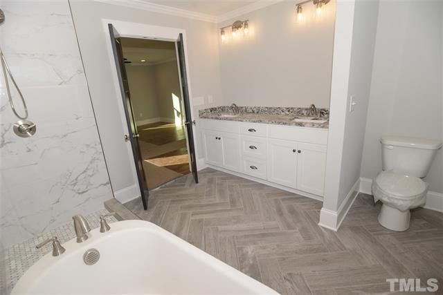 A bathroom with a tub , toilet , sink and shower.