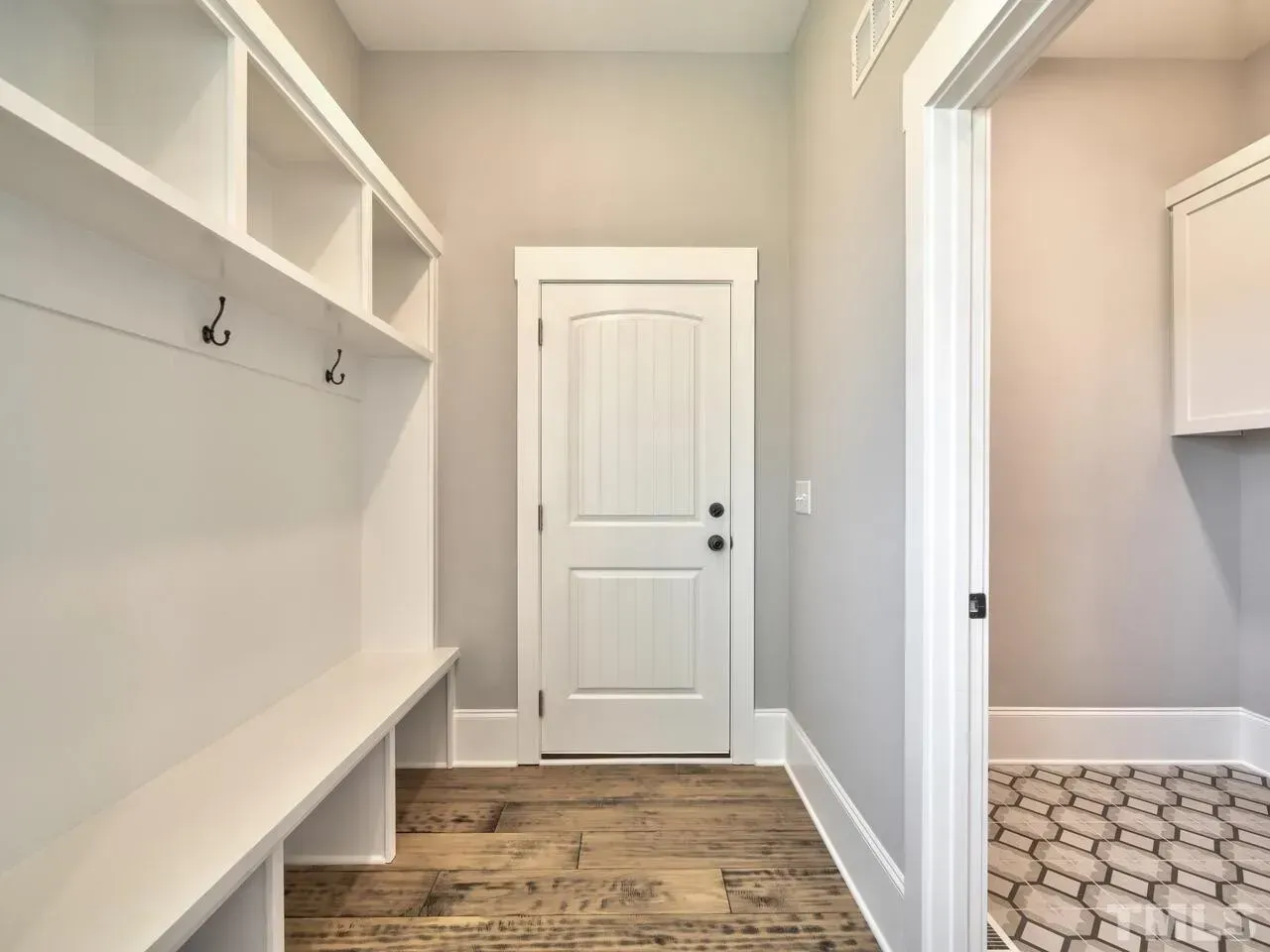 A hallway with a white door and a bench.