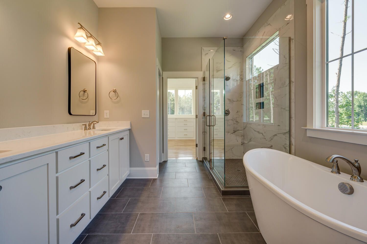 A bathroom with two sinks , a tub , a shower and a window.