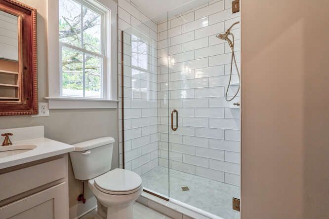 A bathroom with a toilet , sink and shower with a glass door.