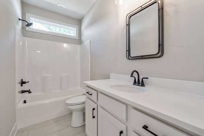 A bathroom with a toilet , sink , mirror and bathtub.