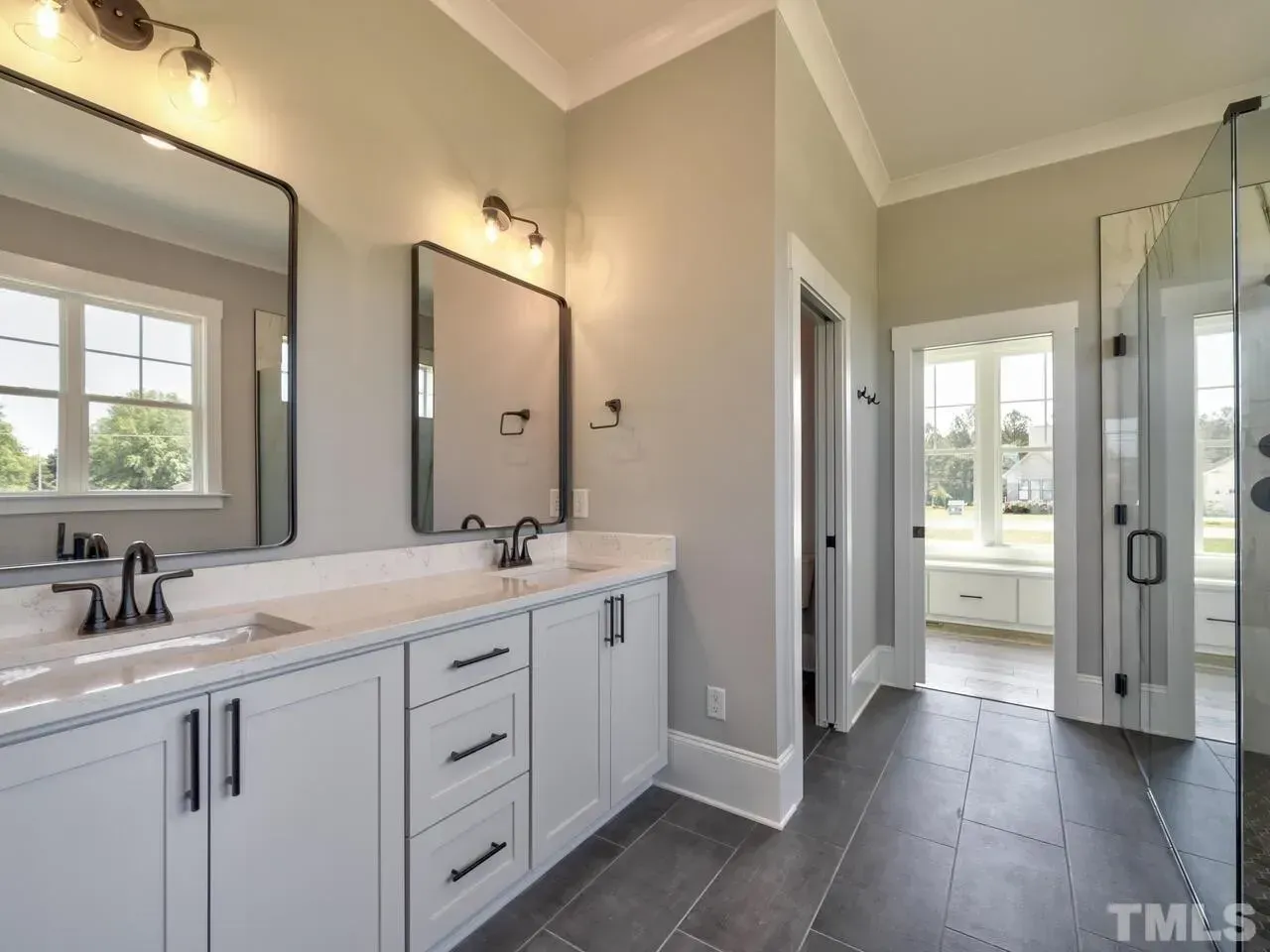 A bathroom with two sinks , two mirrors and a walk in shower.
