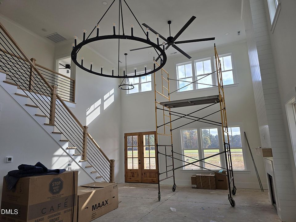A two-story entryway under construction with a chandelier, staircase, and scaffolding.