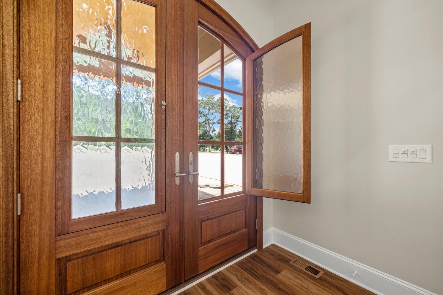 A wooden door with a glass window is open in a room.
