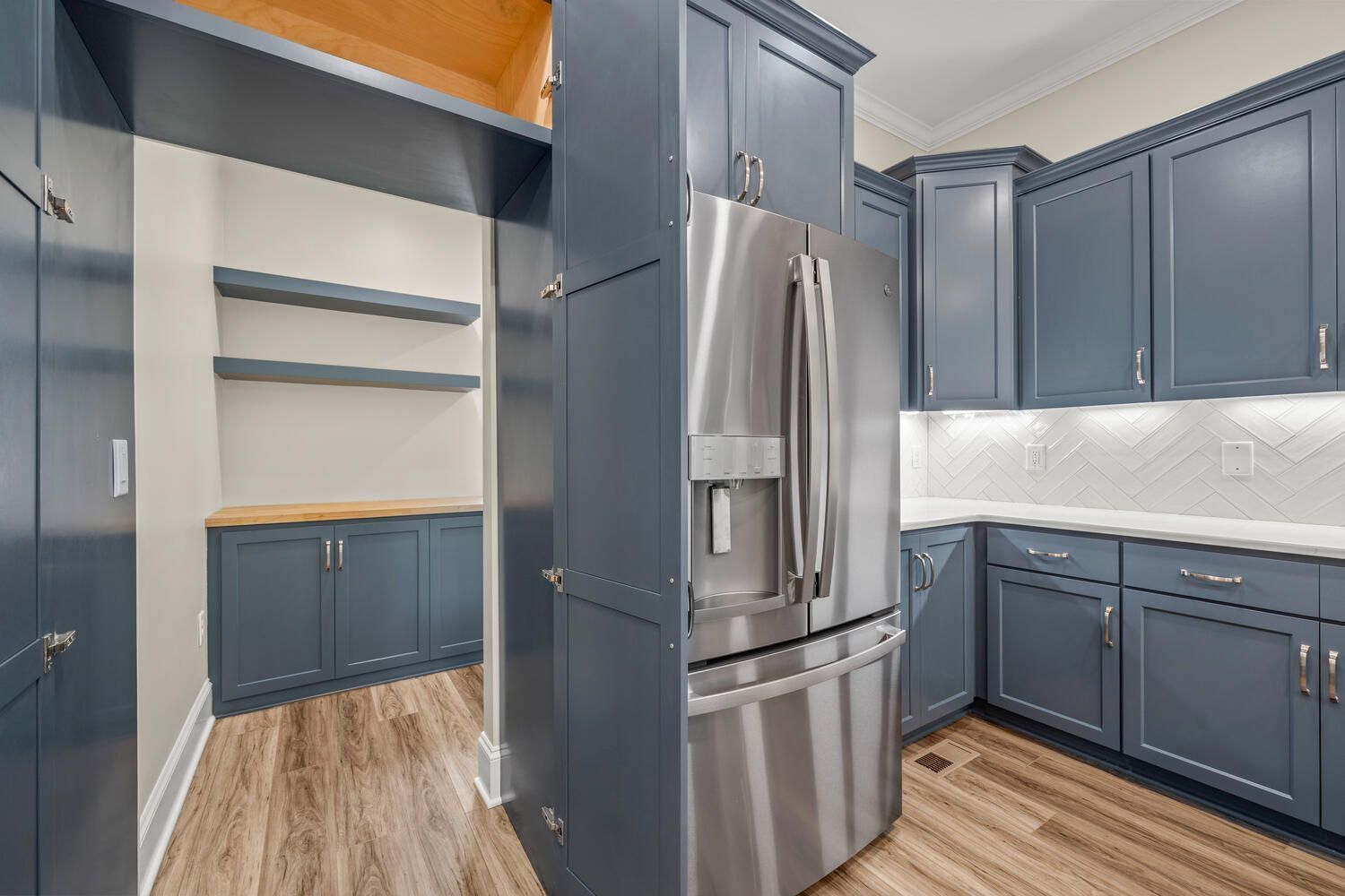 A kitchen with blue cabinets and a stainless steel refrigerator.