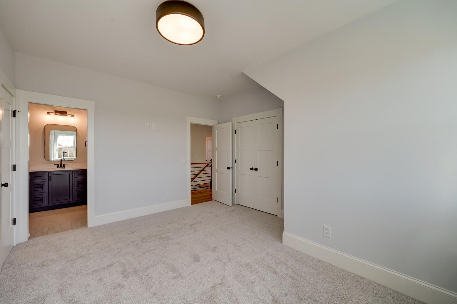An empty bedroom with a staircase leading to a bathroom.