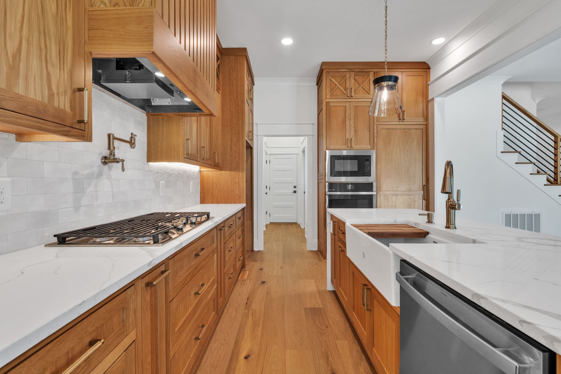 A modern kitchen with wood cabinets, white countertops, and stainless steel appliances.