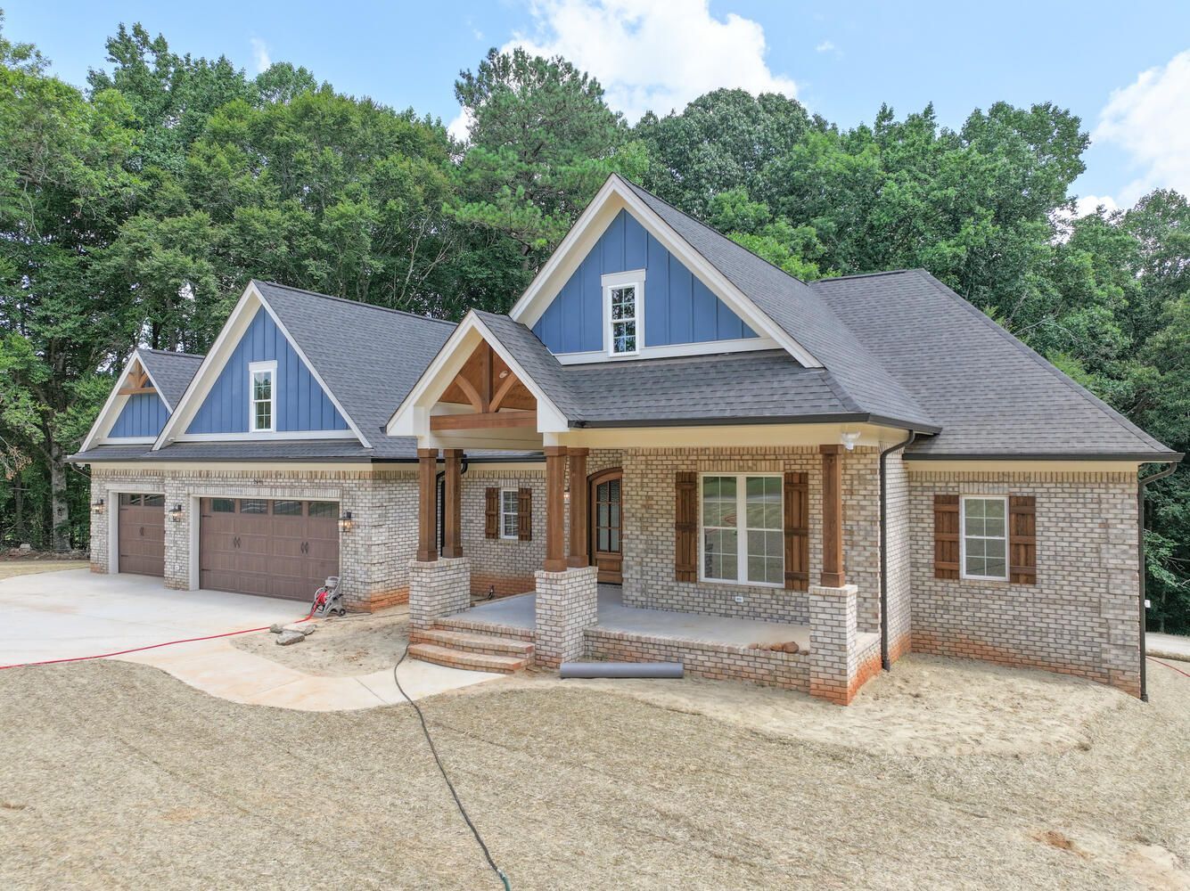 A large brick house with a blue roof is surrounded by trees.