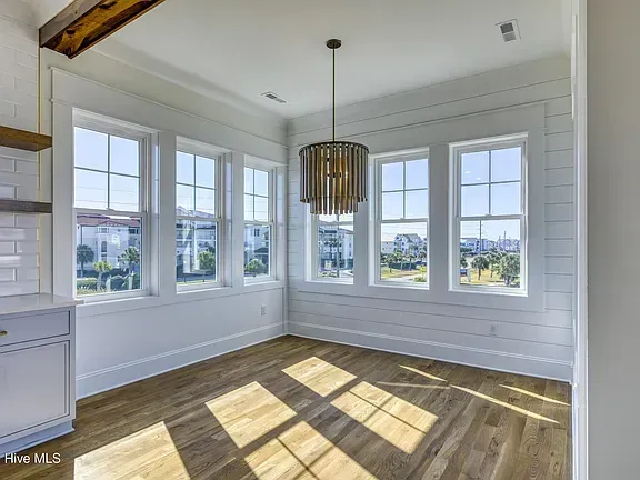 Bright dining room with many windows, wood floors, and a chandelier.