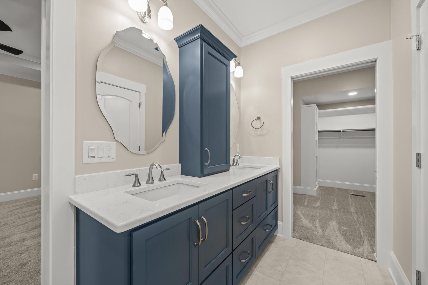 A bathroom with two sinks , a mirror and blue cabinets.