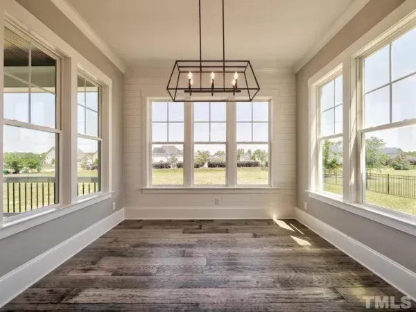 An empty room with a lot of windows and a chandelier