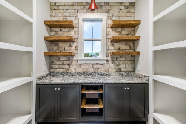 A walk in pantry with a brick wall and a window.