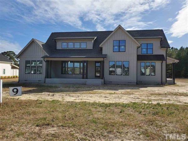 A large house with a lot of windows is sitting on top of a dirt field.