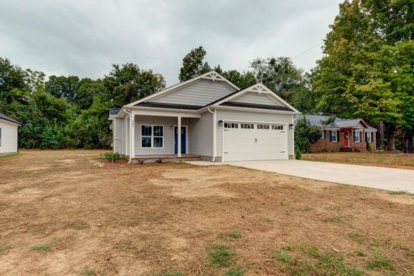 A white house is sitting on top of a dirt field.