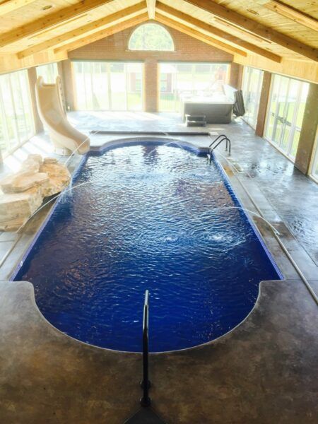 A large indoor swimming pool with a slide and a hot tub.