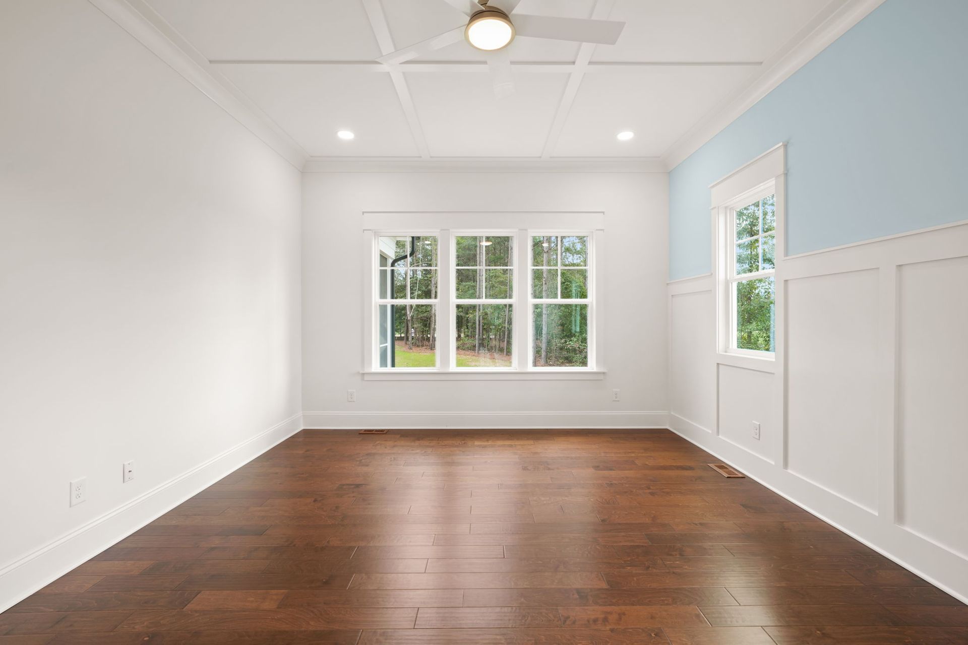 An empty room with hardwood floors and a ceiling fan