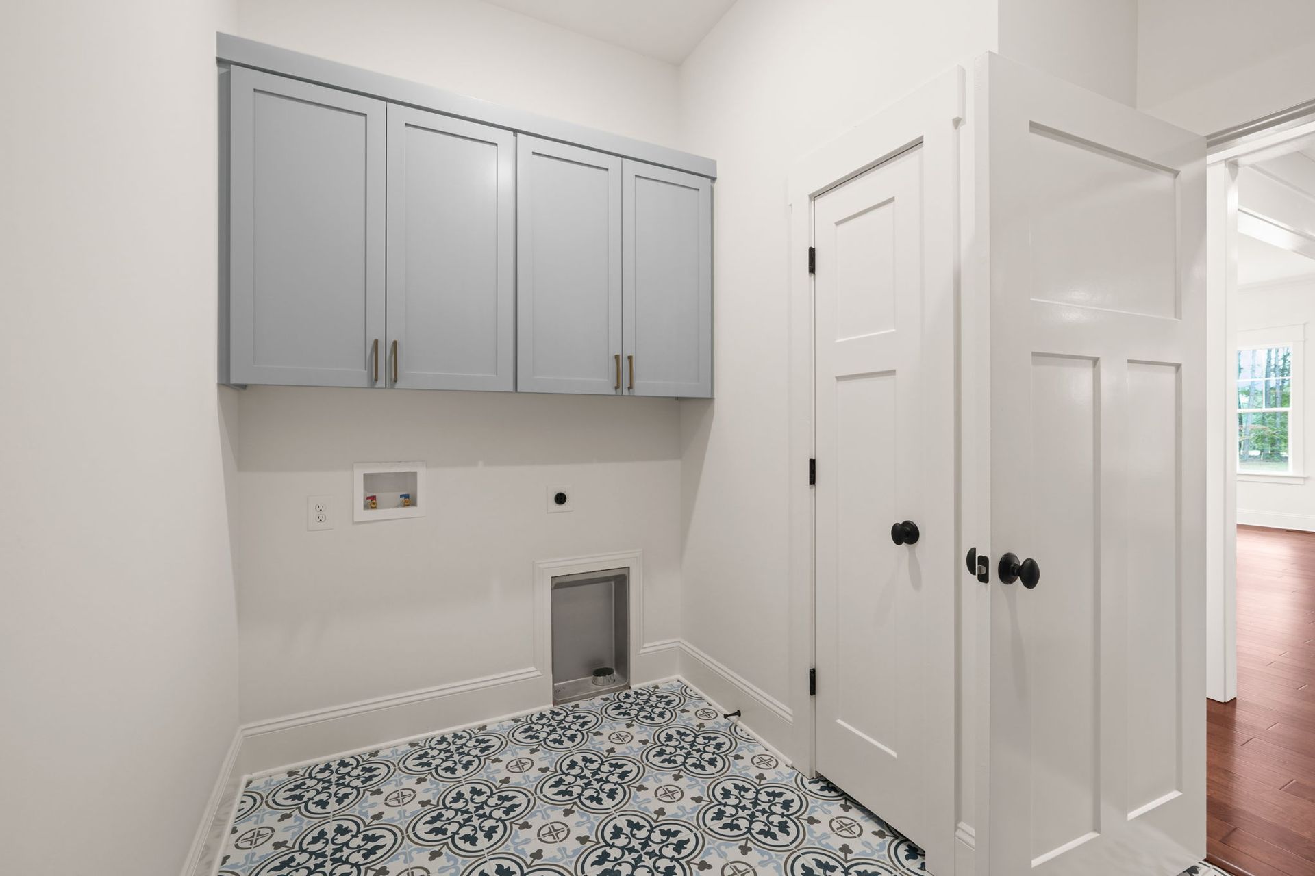 A laundry room with white cabinets and a blue and white tile floor.