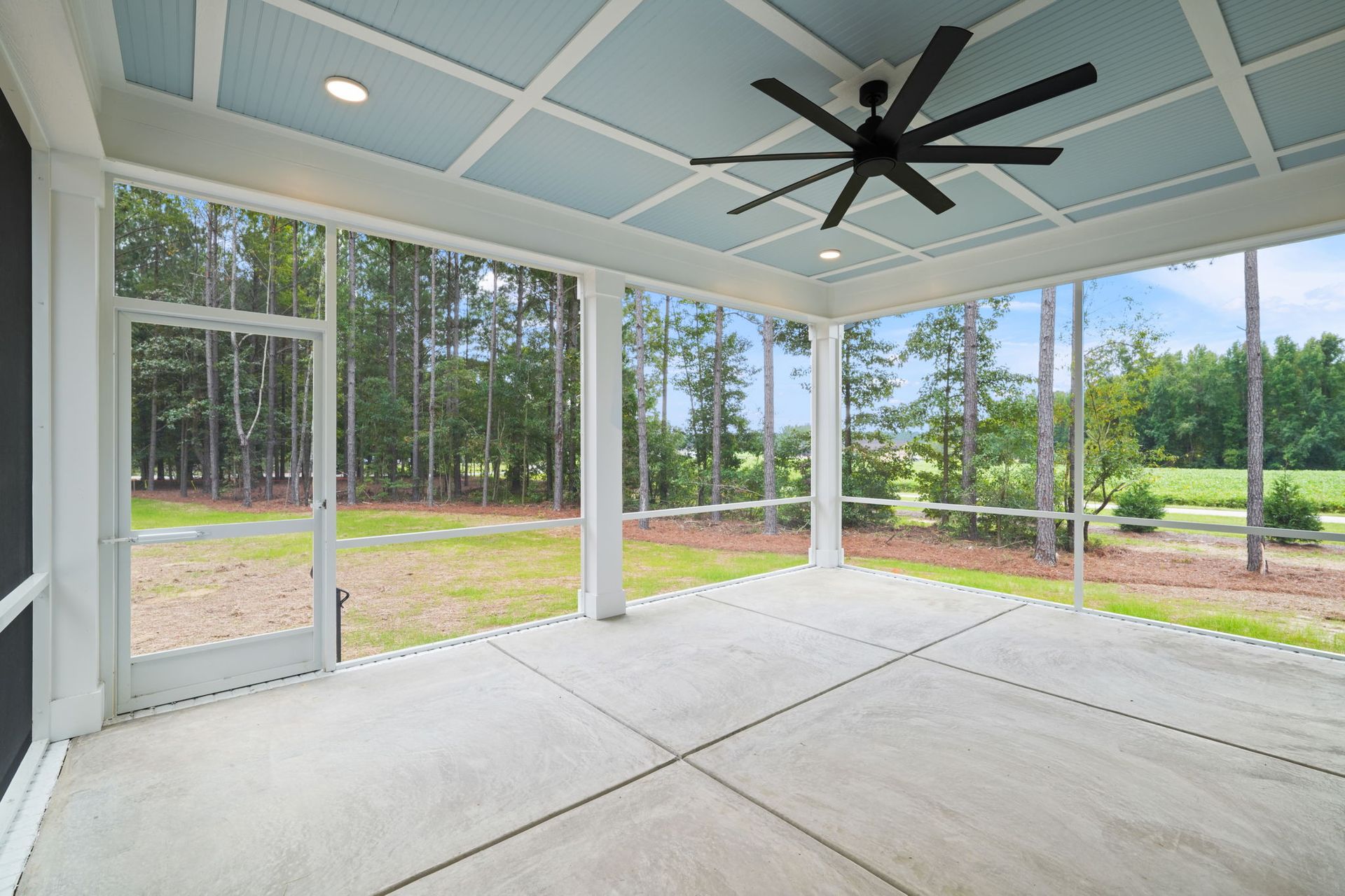 A screened in porch with a ceiling fan and a lot of windows.
