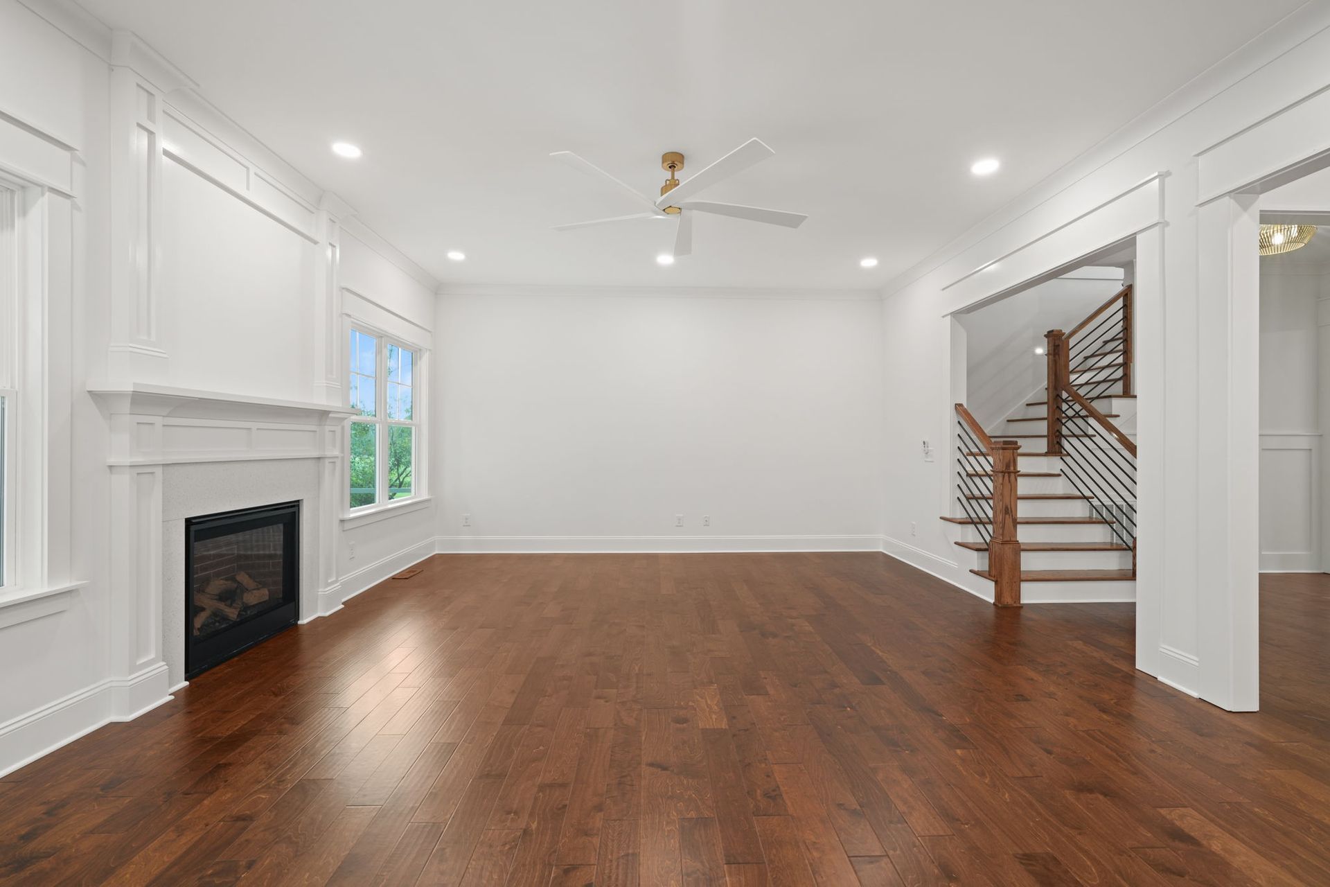 An empty living room with hardwood floors and a fireplace.