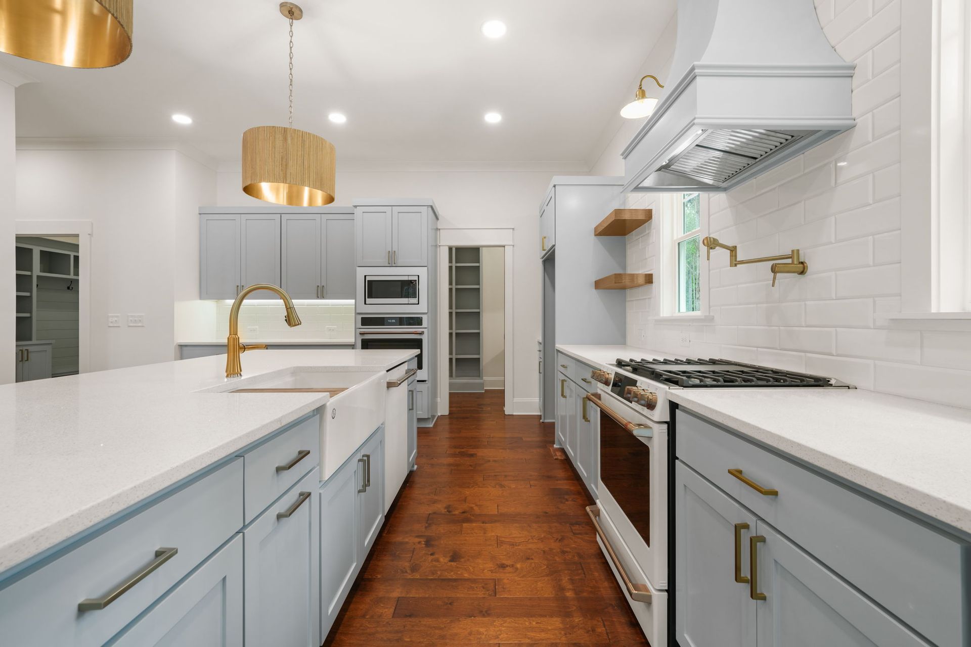 A kitchen with blue cabinets , white counter tops , a stove and a sink.