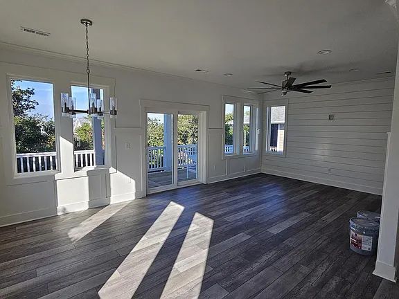 An empty living room with hardwood floors and a ceiling fan