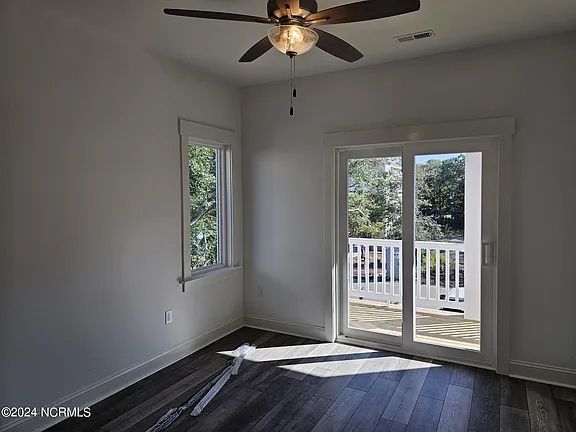 An empty room with a ceiling fan and sliding glass doors