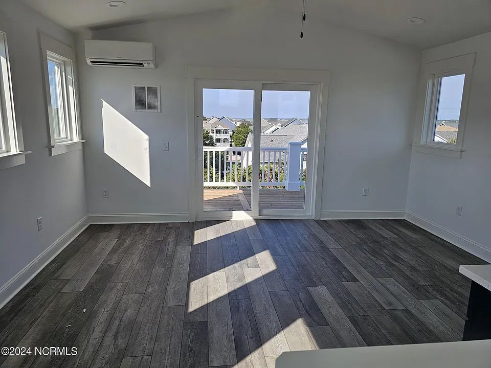 A living room with hardwood floors and sliding glass doors leading to a balcony