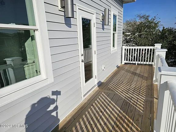 A large deck with a white railing and sliding glass doors on the side of a house