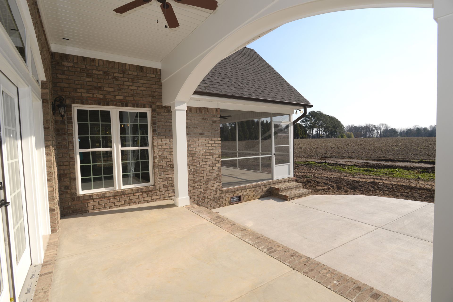 A brick house with a screened in porch and a ceiling fan.