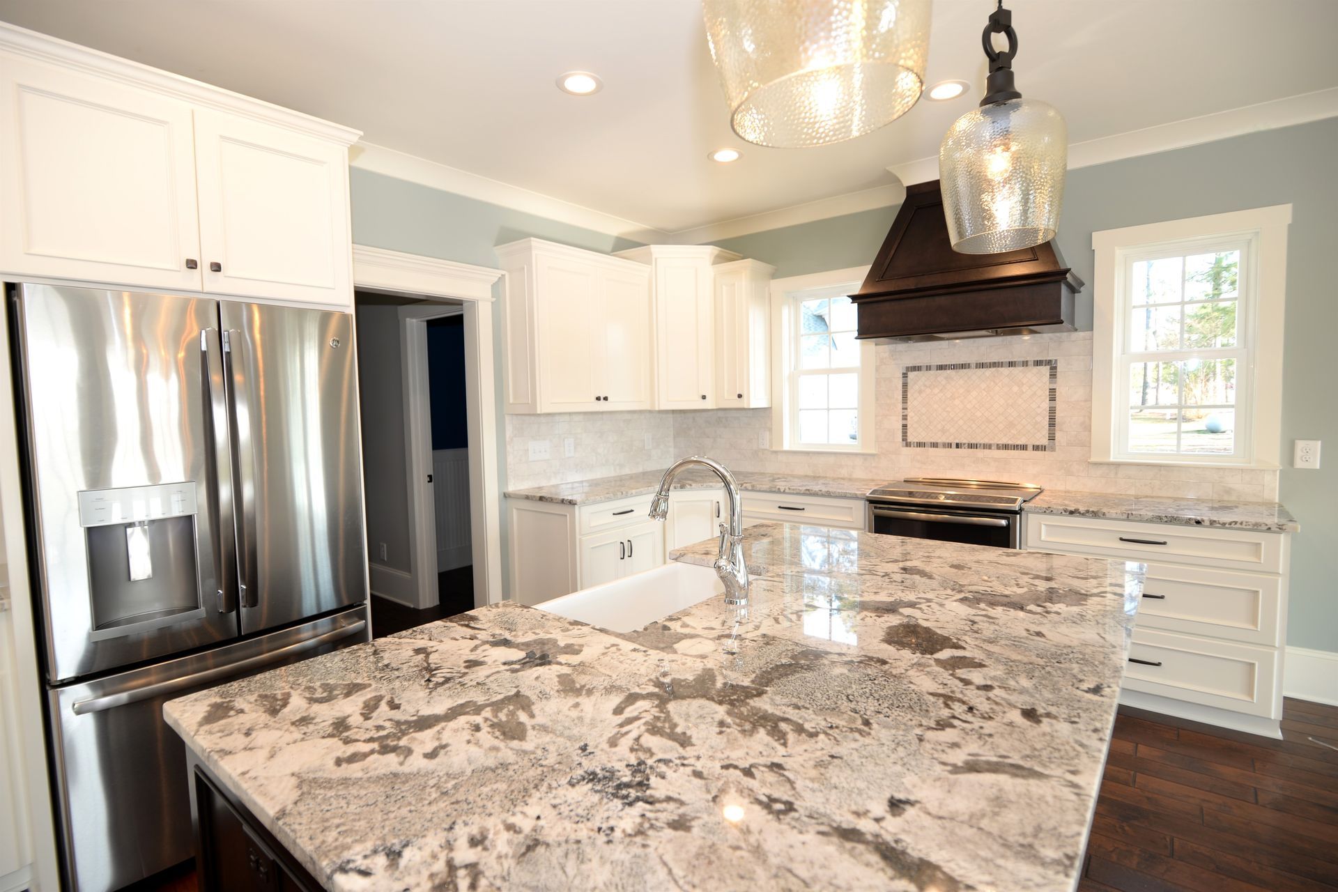 A kitchen with granite counter tops , stainless steel appliances , and white cabinets.