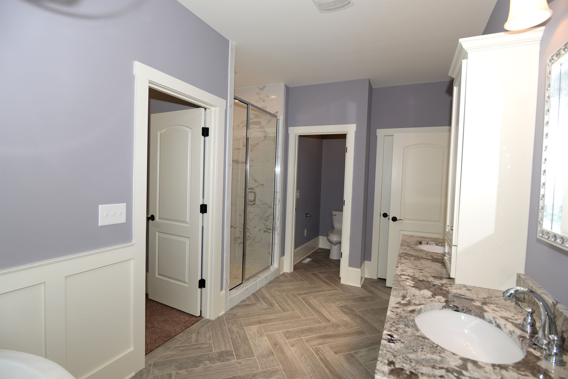 A bathroom with two sinks , a toilet , and a walk in shower.