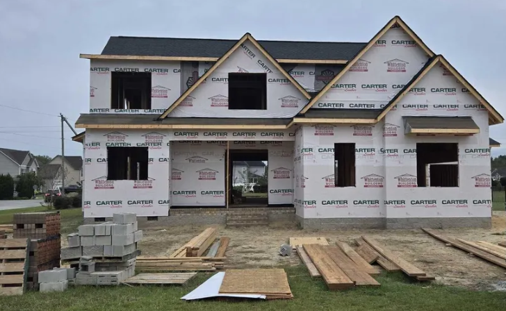 A house under construction with a lot of wood in front of it