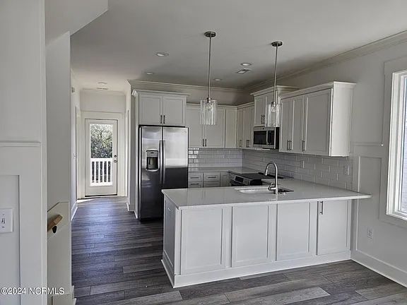 A kitchen with white cabinets, stainless steel appliances, and a large island.
