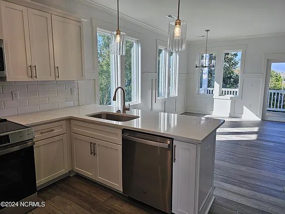 A kitchen with white cabinets, stainless steel appliances, and a large island.