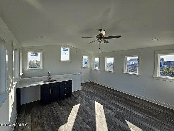 An empty room with a ceiling fan and a sink.