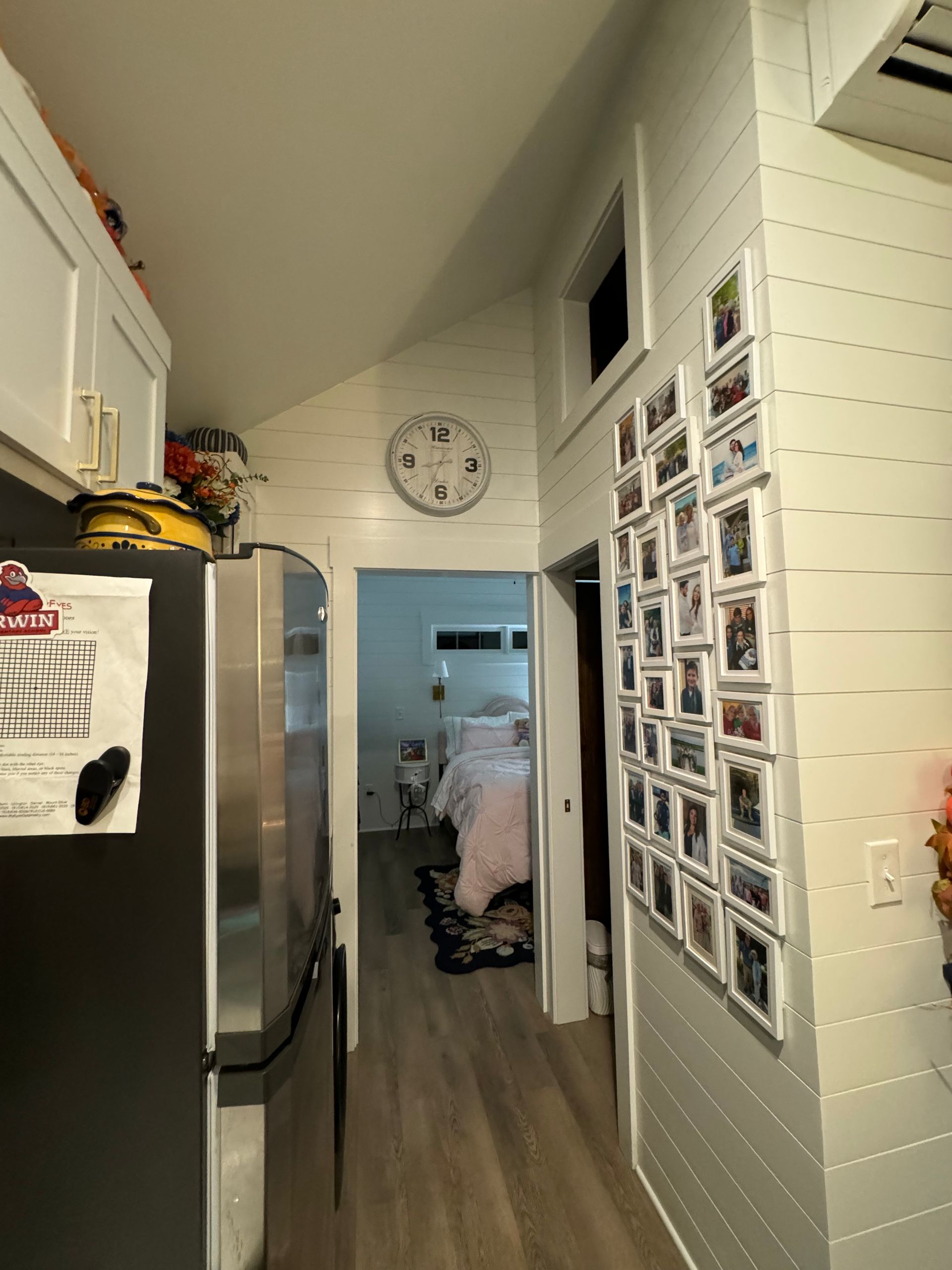 A kitchen with a refrigerator and a clock on the wall