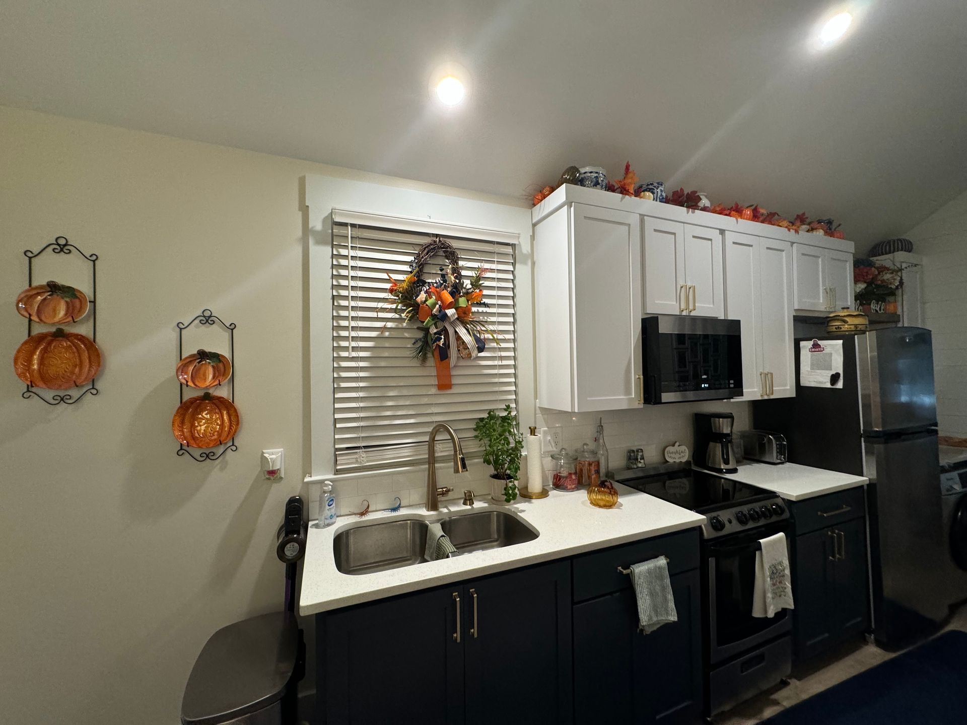A kitchen with a sink, stove, microwave, and refrigerator