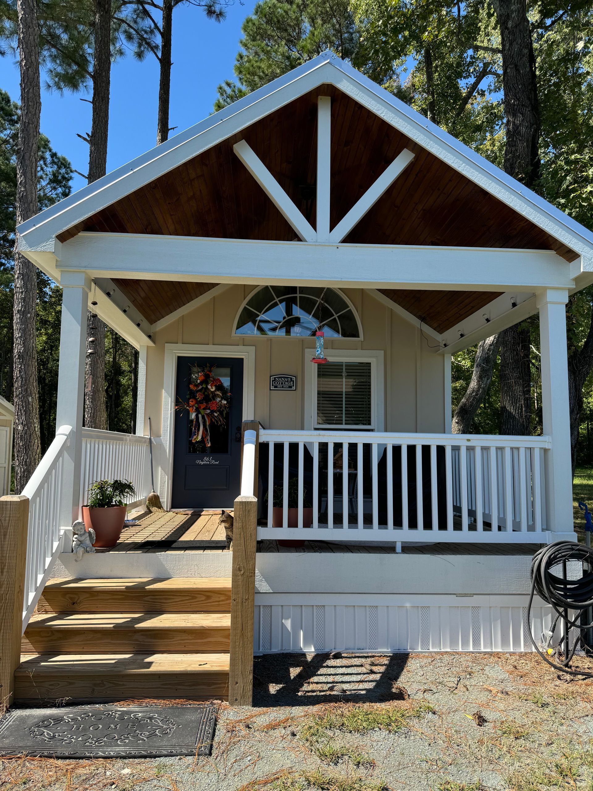 A small house with a porch and stairs is surrounded by trees