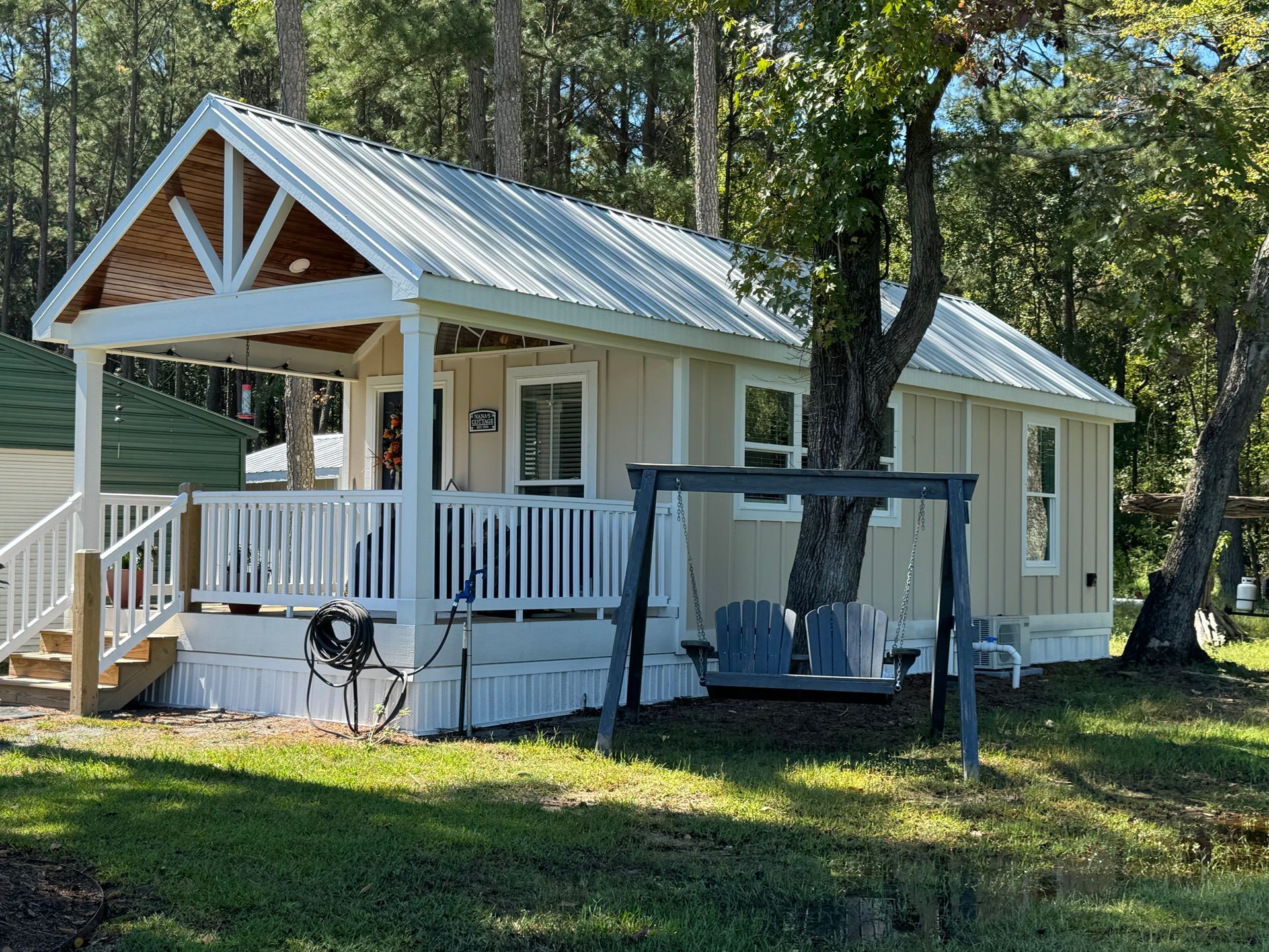 A small house with a porch and swings in front of it