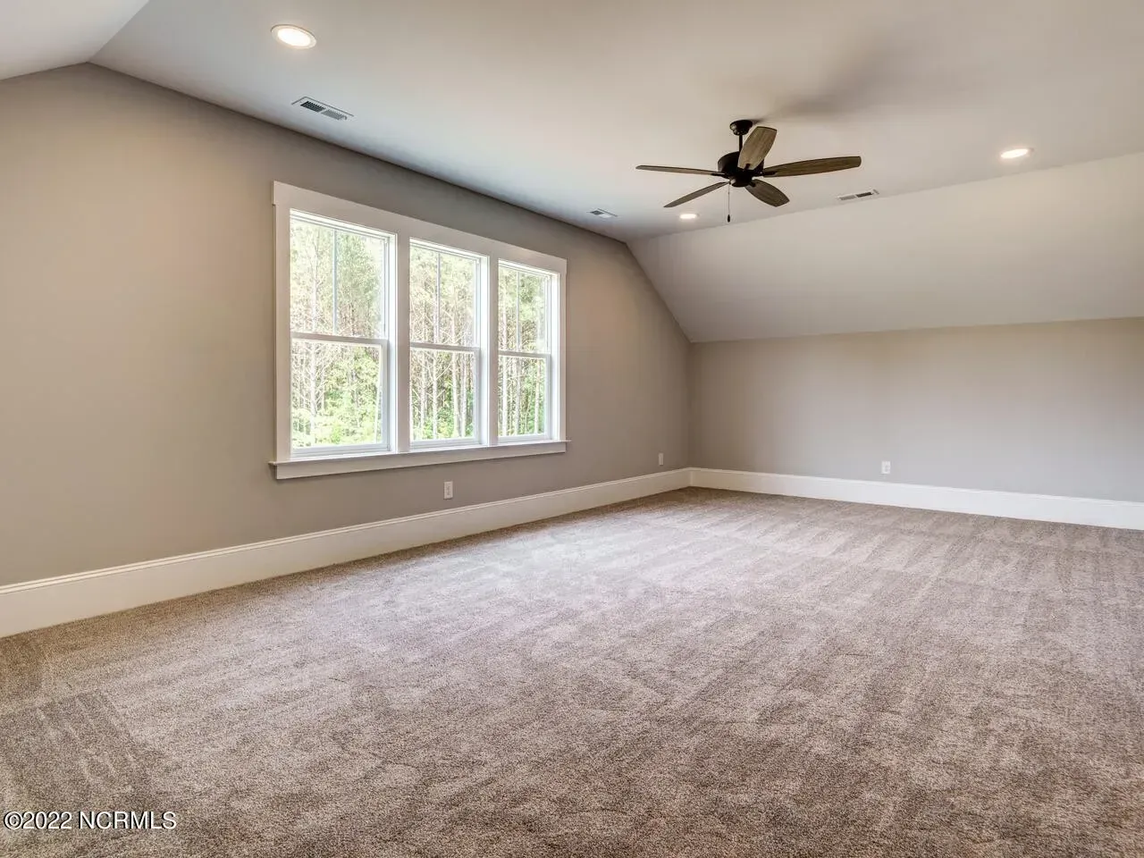 An empty bedroom with a ceiling fan and two windows.