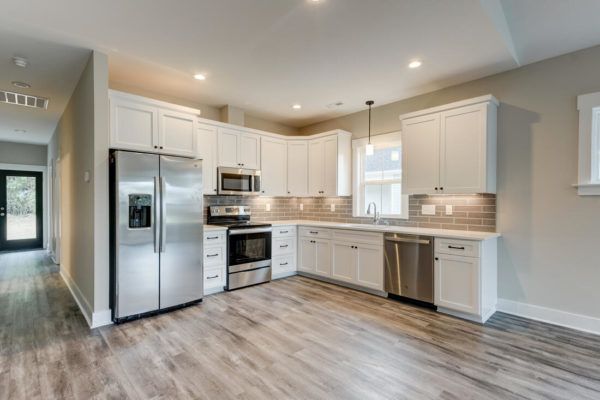 A kitchen with white cabinets , stainless steel appliances , and hardwood floors.