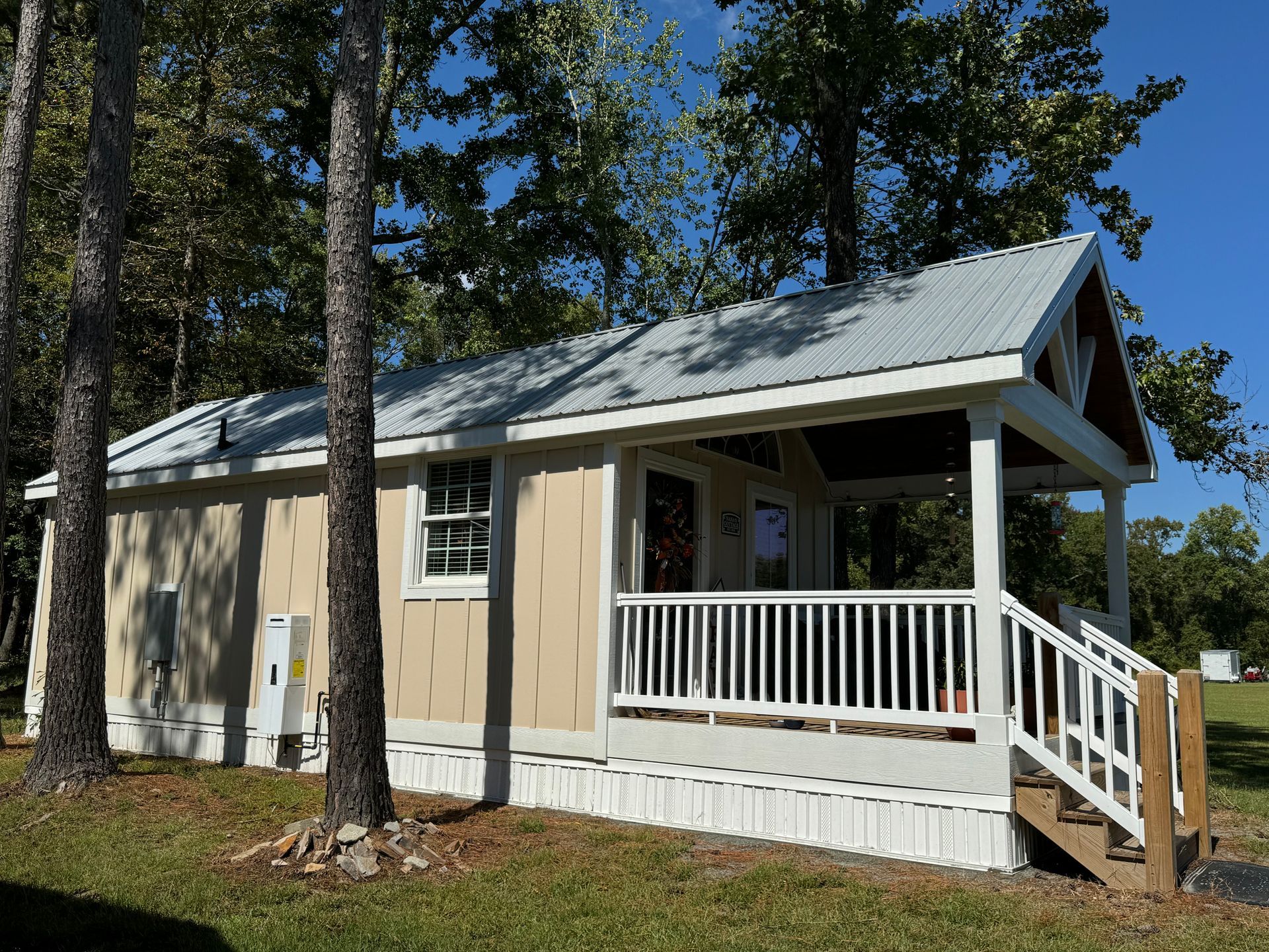 A small house with a porch and stairs surrounded by trees