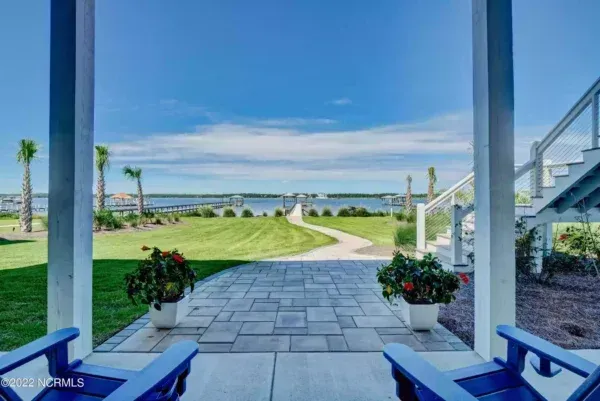 Two blue chairs are sitting on a porch overlooking a body of water.