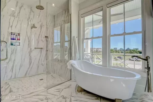 A bathroom with a tub , shower , and window.