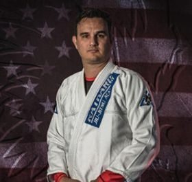 Martial artist in a white gi with red gloves standing before a U.S. flag backdrop