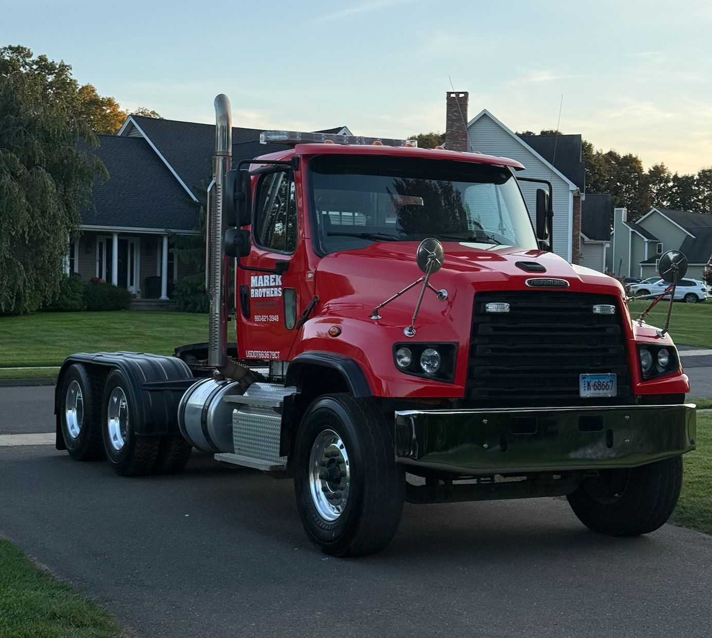 Red semi-truck cab parked on a residential street at dusk