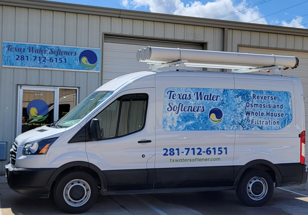 White Texas Water Softeners van parked outside a business, blue and white logo, phone number visible.